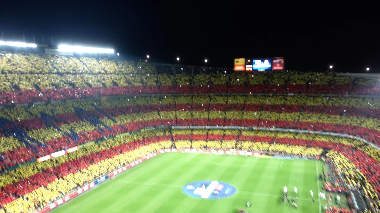 Floodlit stadium at night with packed stands during a match